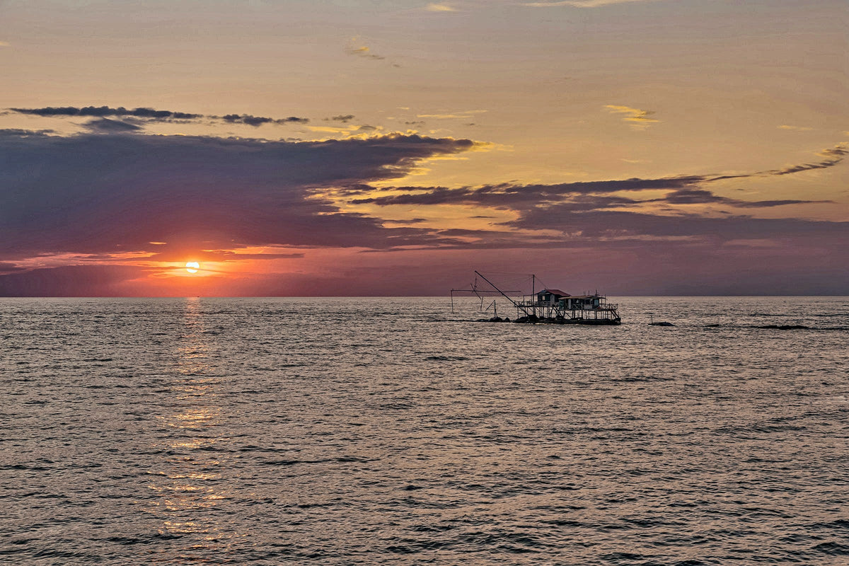 Sunset over the sea at Marina di Pisa, with a fishing hut on stilts