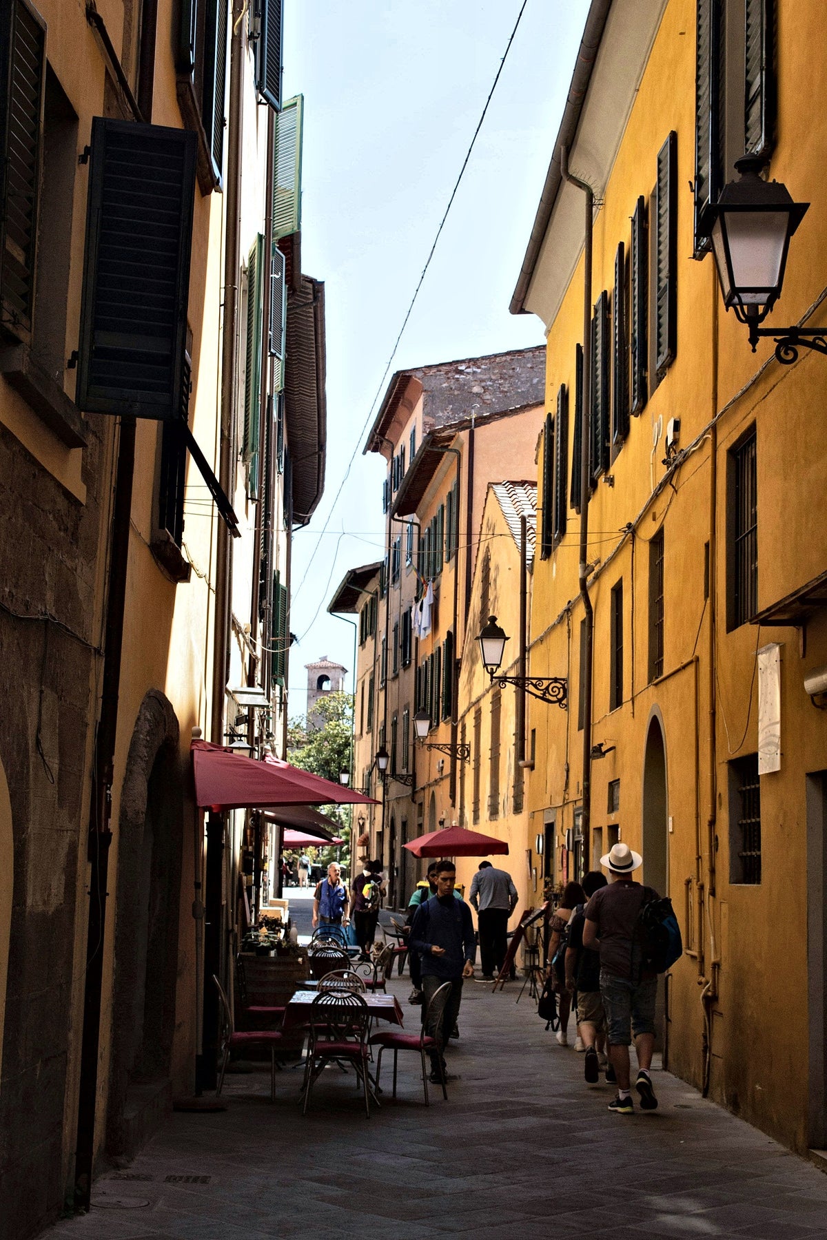 Ochre facades and outdoor tables in a lane of the historic centre