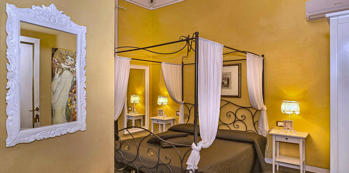 A canopy bed in a warm yellow room at Hotel Pisa Tower
