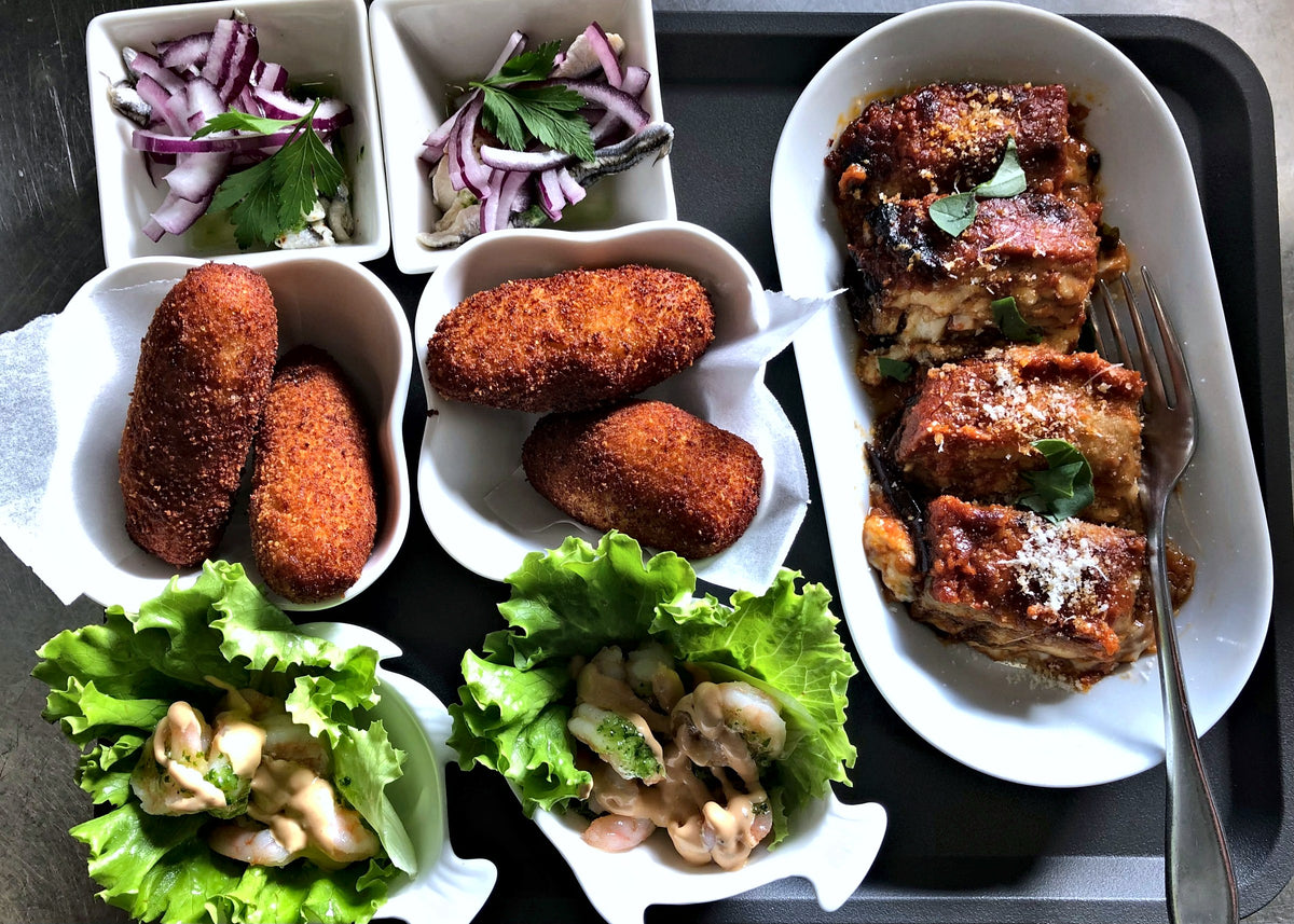 A tray of croquettes, parmigiana and salads at Sugo e Camicia