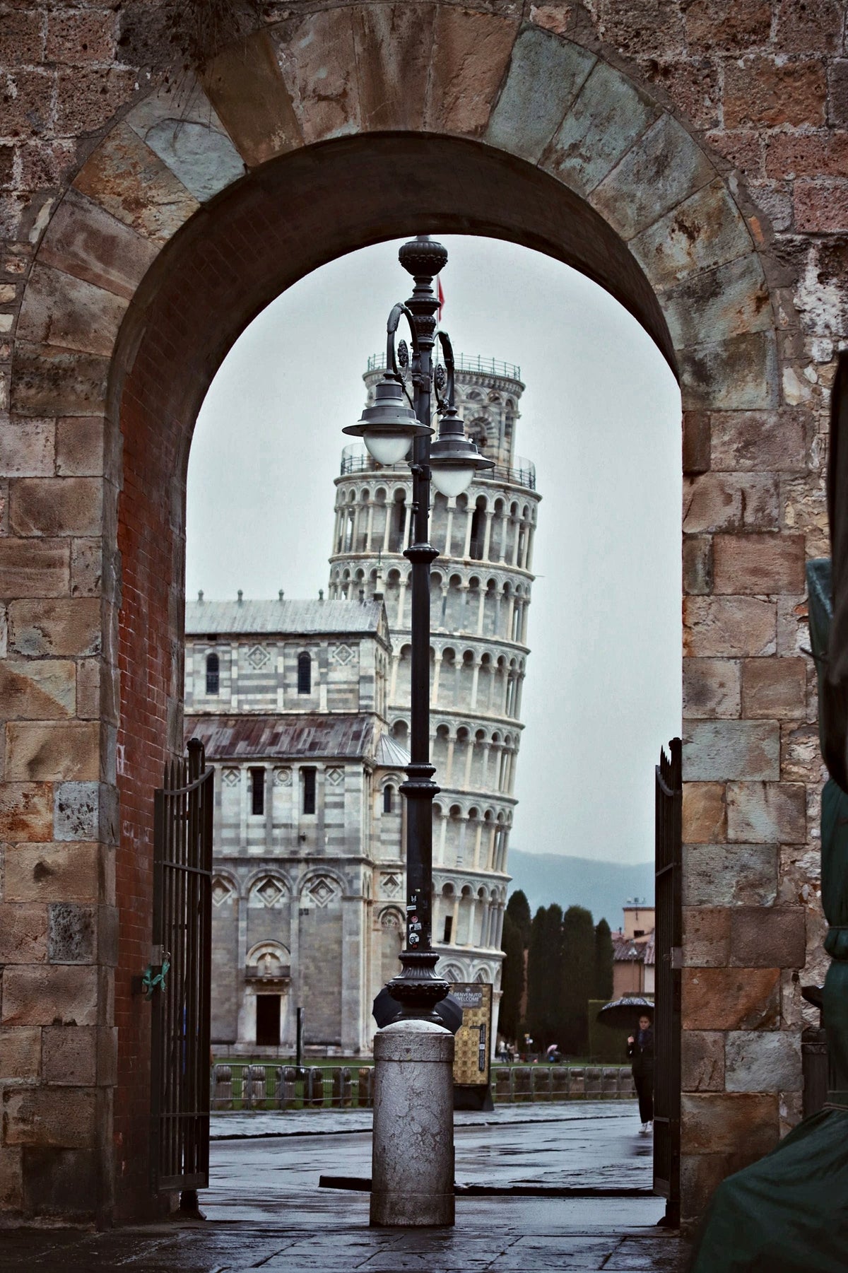 The leaning tower framed by a medieval stone archway
