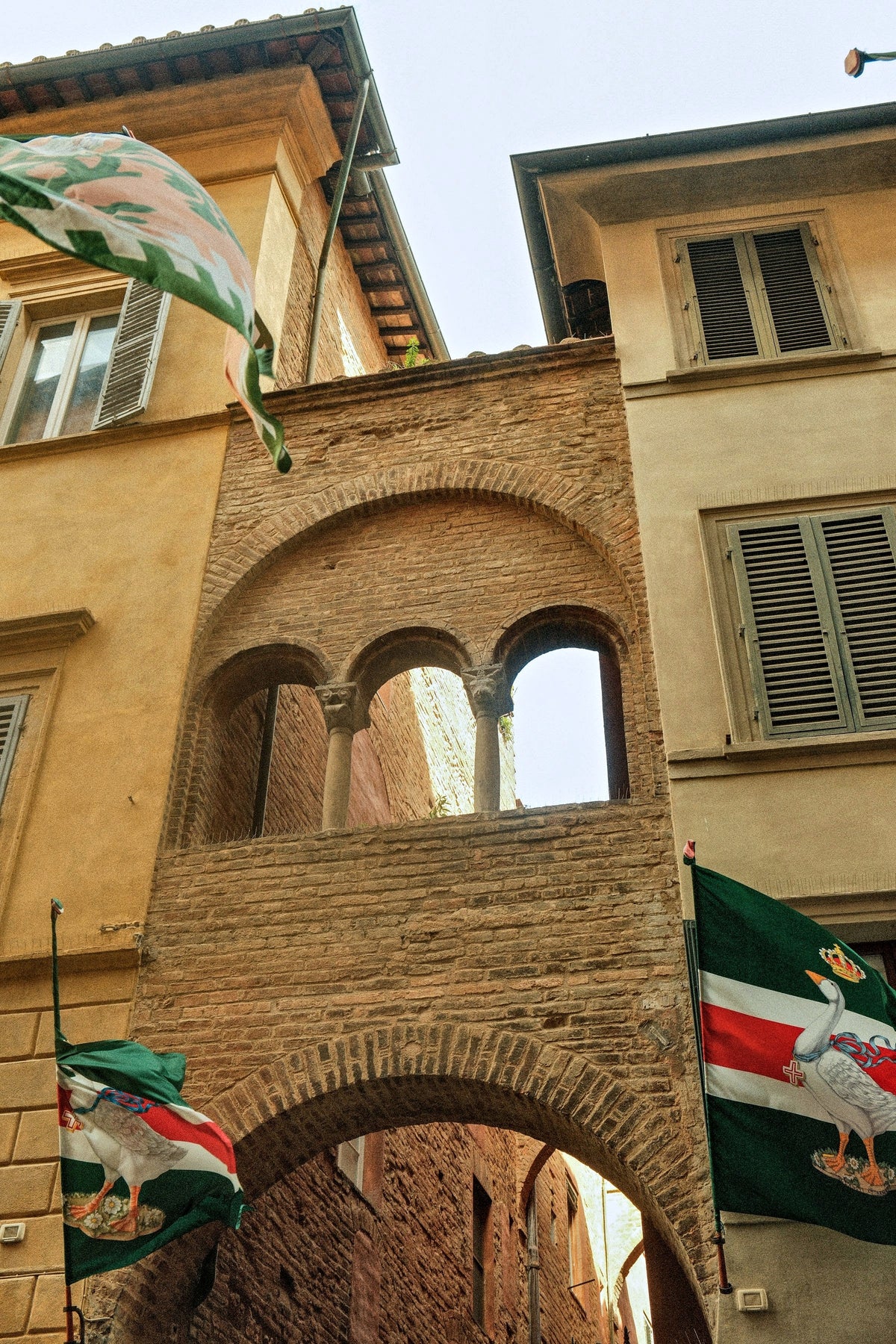 Contrada flags above a brick arch at golden hour