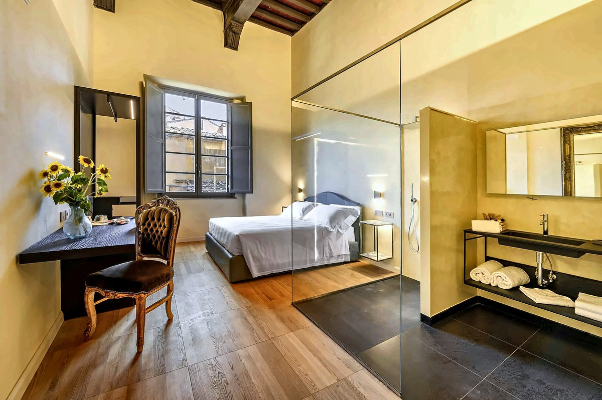 Suite with a glass-walled bathroom and an antique chair at Palazzo Patrizi
