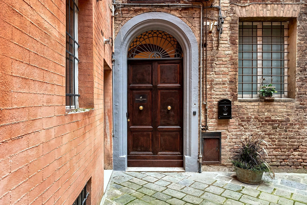 Arched wooden entrance door in the brick courtyard of Palazzo Patrizi