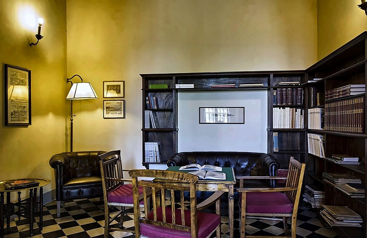 Library lounge with bookcases and a leather sofa at Palazzo Ravizza