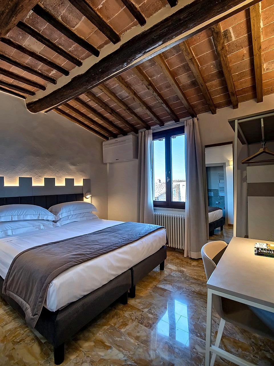 Double room under a beamed ceiling at Torre del Fuggisole