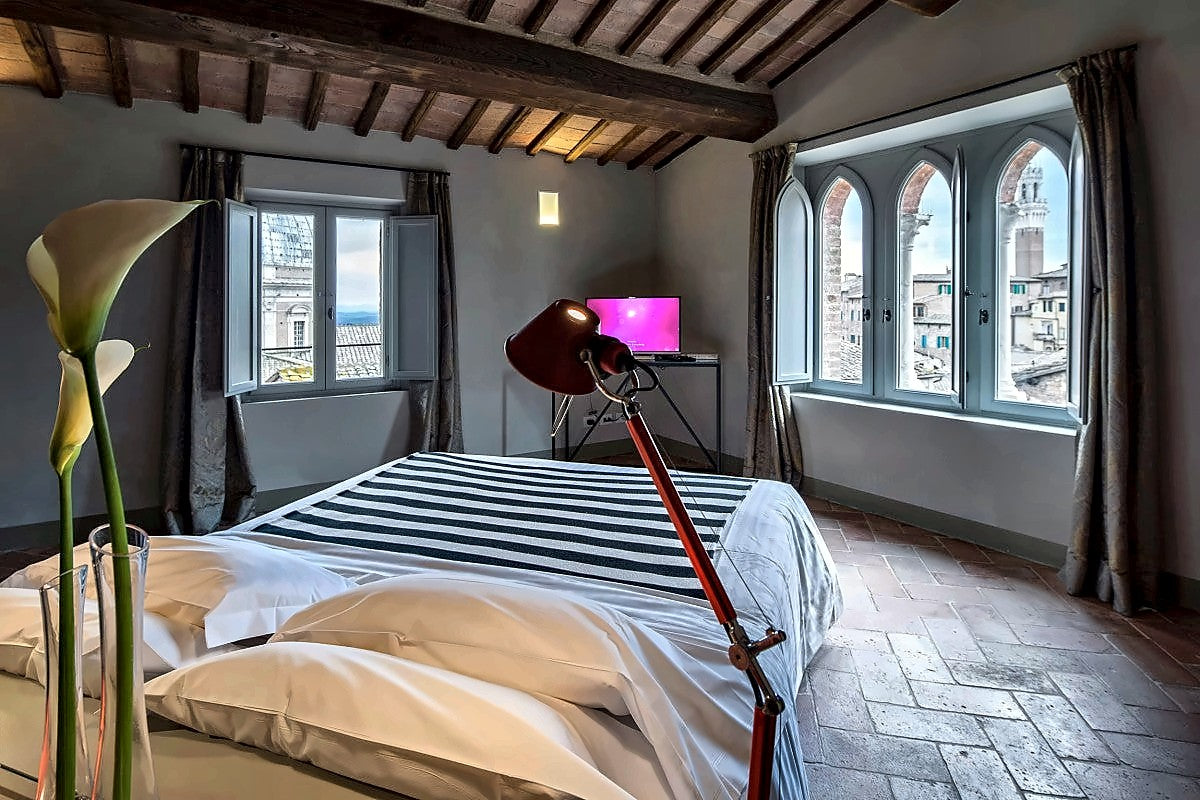 Suite with a beamed ceiling and arched windows at Hotel Palazzetto Rosso
