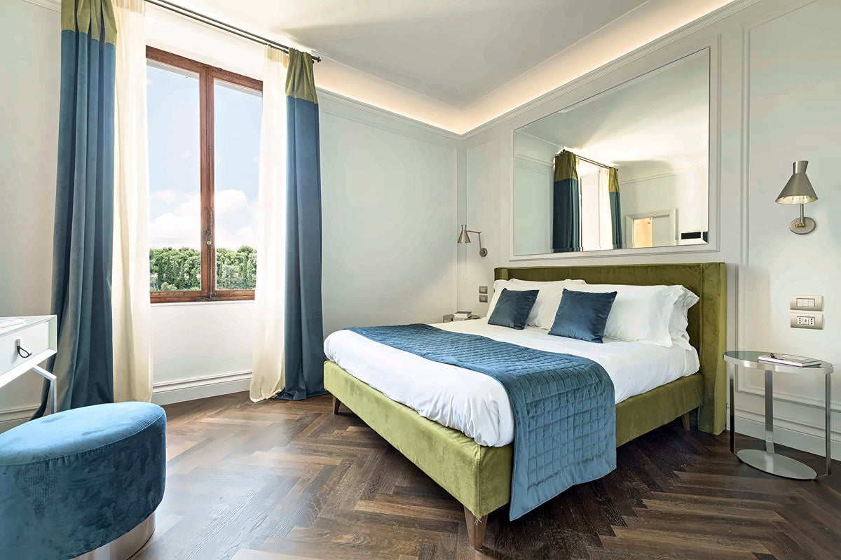 Double room with a green upholstered bed and blue curtains at Hotel Chiusarelli