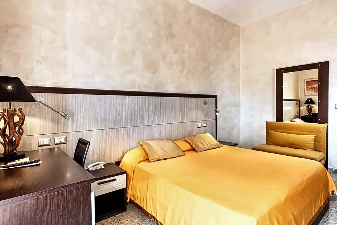 Double room with a yellow bedspread and a work desk at Hotel Minerva