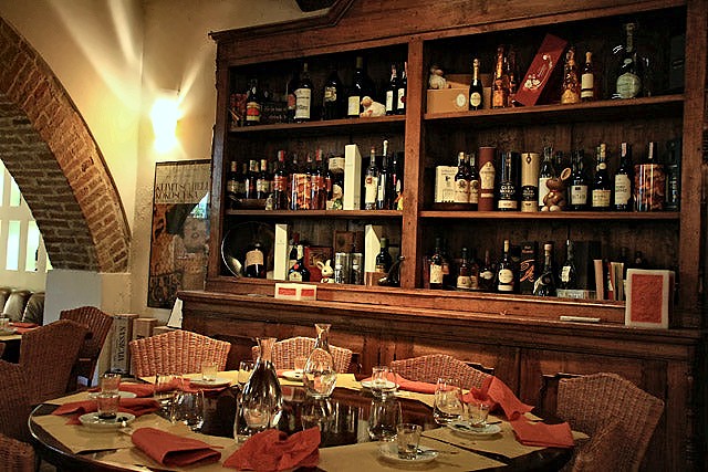 Tables laid beside a wall of wine bottles at Compagnia dei Vinattieri