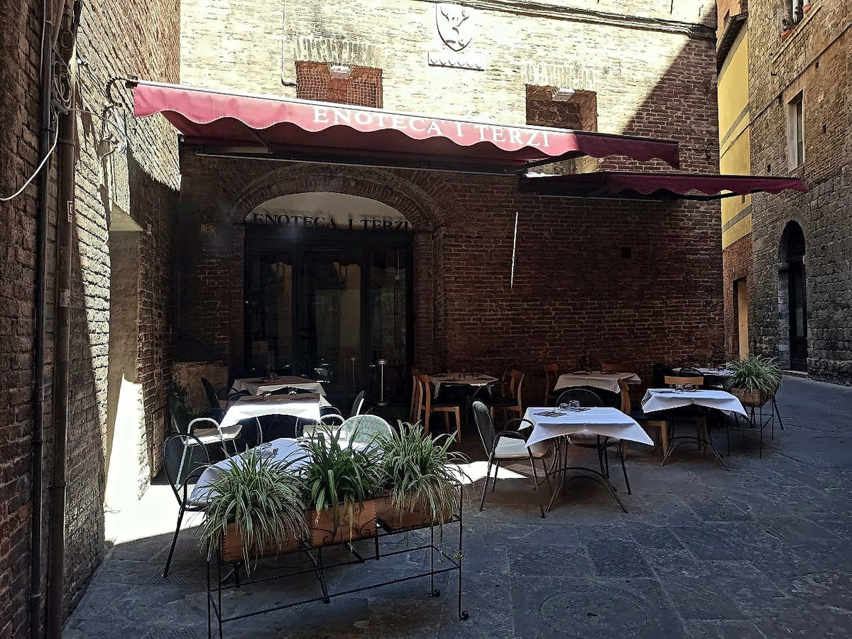 Outdoor tables under an awning on Via dei Termini at Enoteca I Terzi