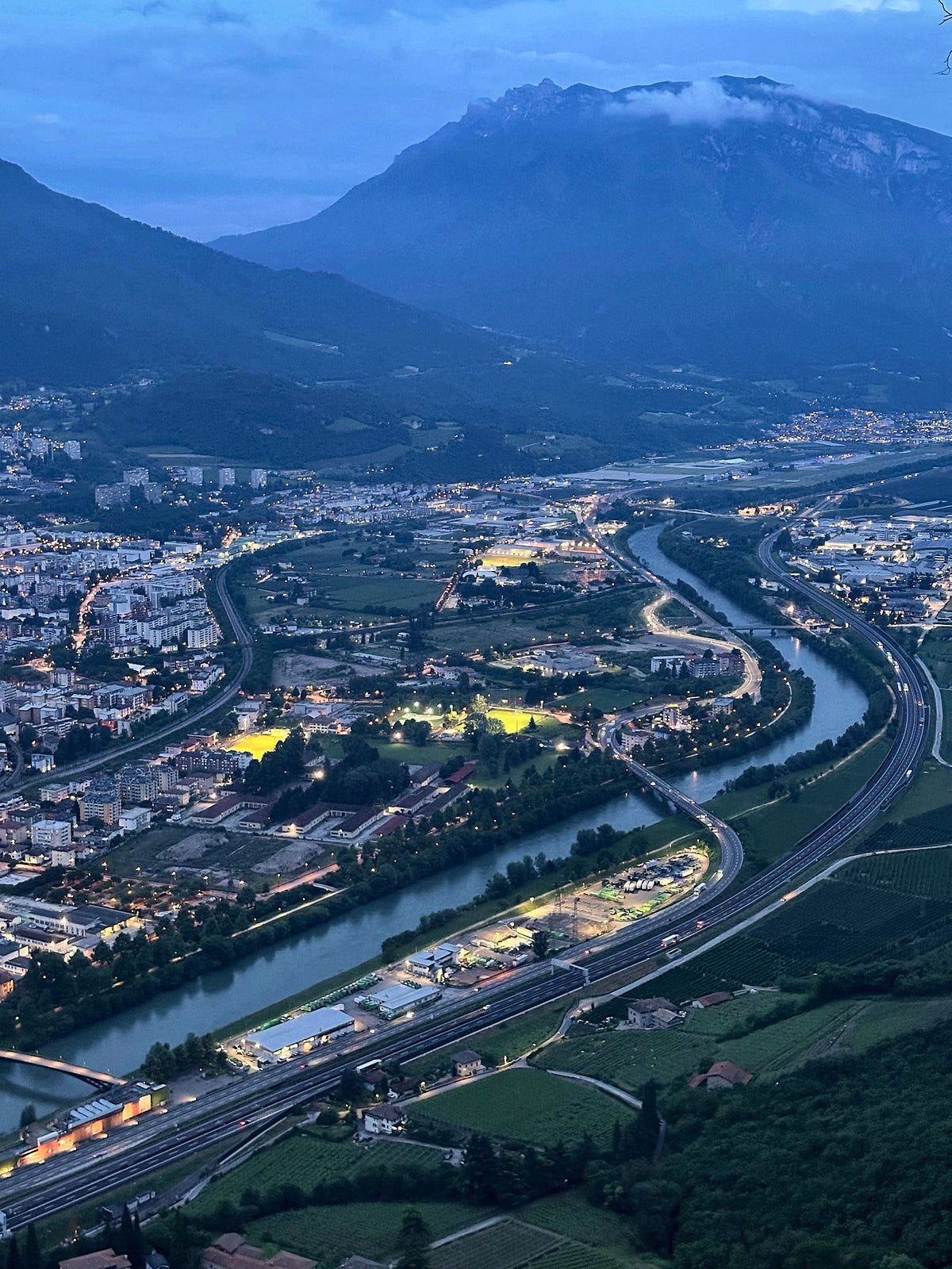 Aerial evening view of the city, the Adige and the mountains