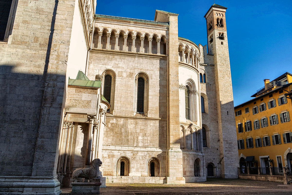 Sunlit flank and apse of Trento Cathedral with its bell tower