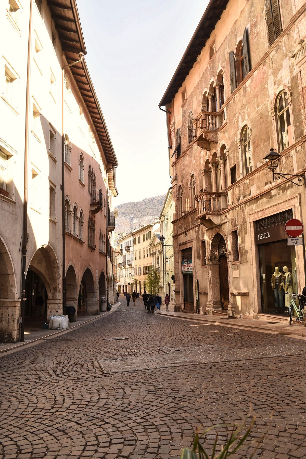 Cobbled street and arcades in the historic centre in warm sunlight