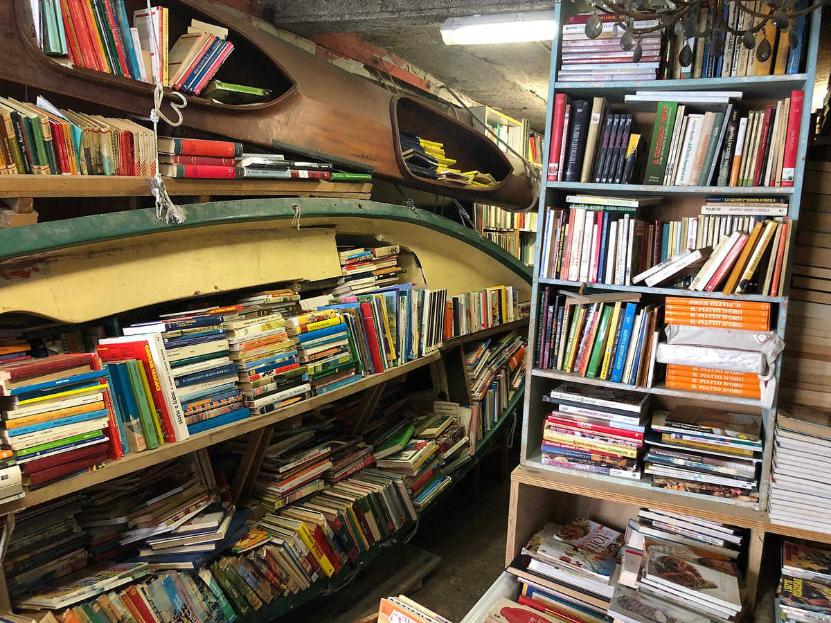 Books and a boat inside Libreria Acqua Alta, Venice