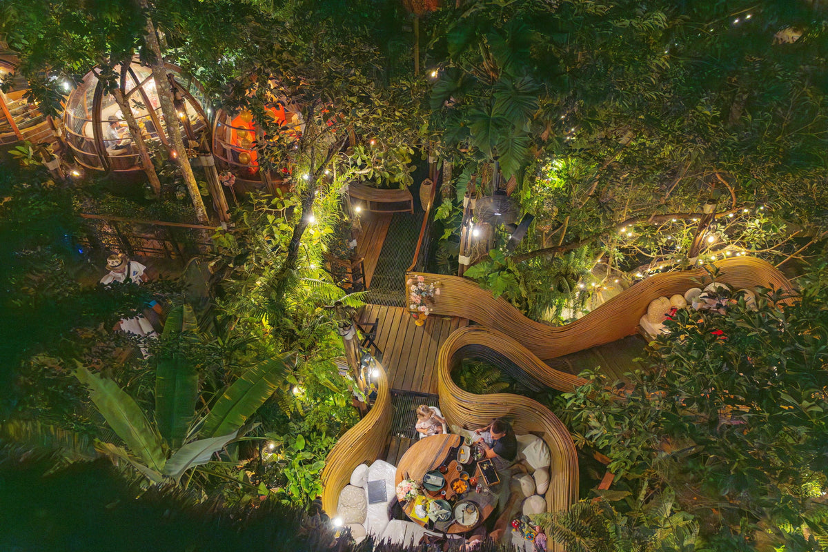 Aerial view of nest-shaped jungle dining seats lit at night at Three Monkeys