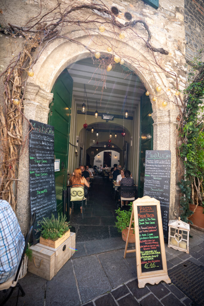 The arched entrance and courtyard tables of Latteria San Fedele