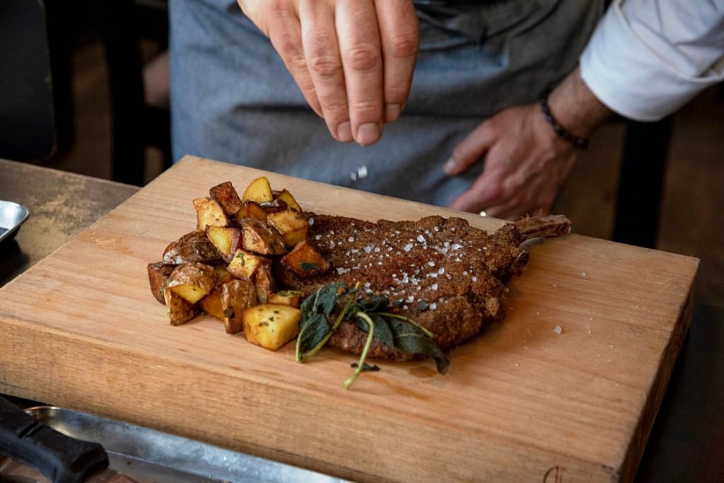 A grilled bone-in chop with roast potatoes at Ratanà