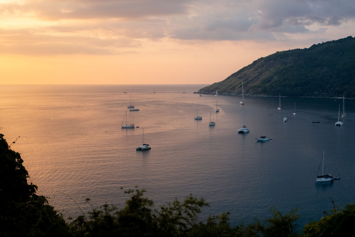Sailboats and yachts anchored in a Phuket bay at sunset