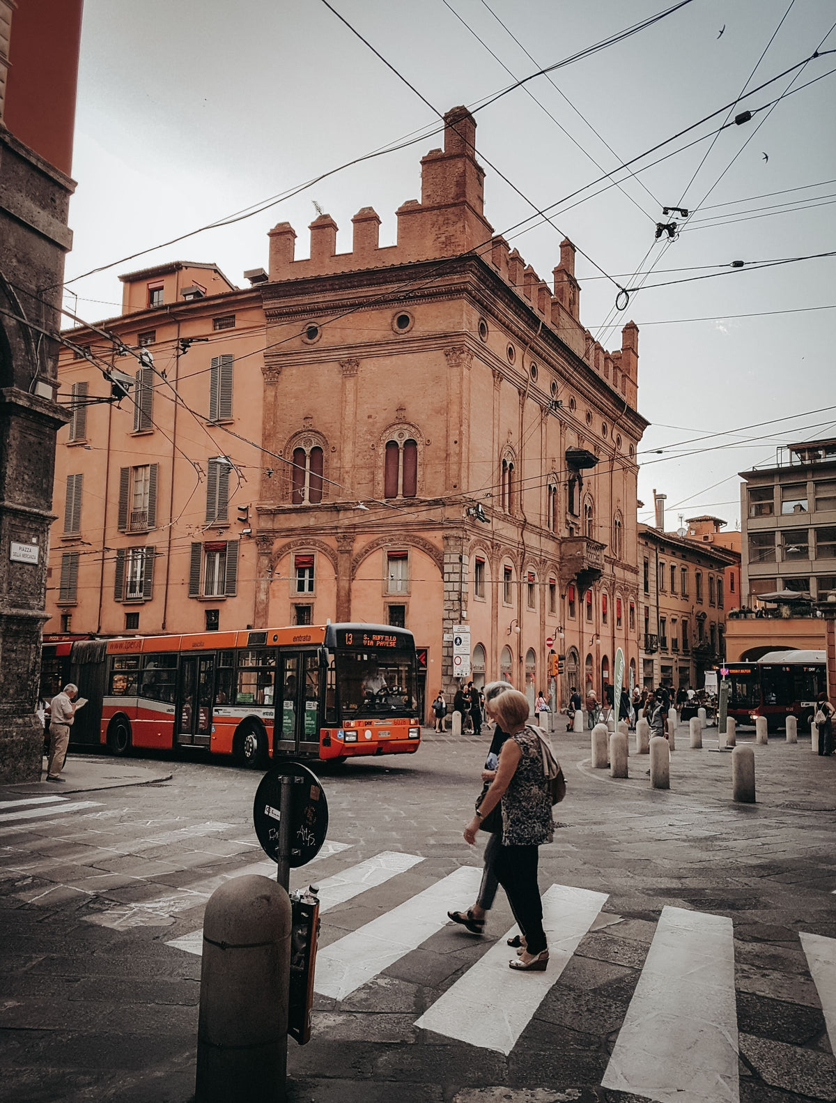 Pedestrians crossing a busy intersection as a red bus passes