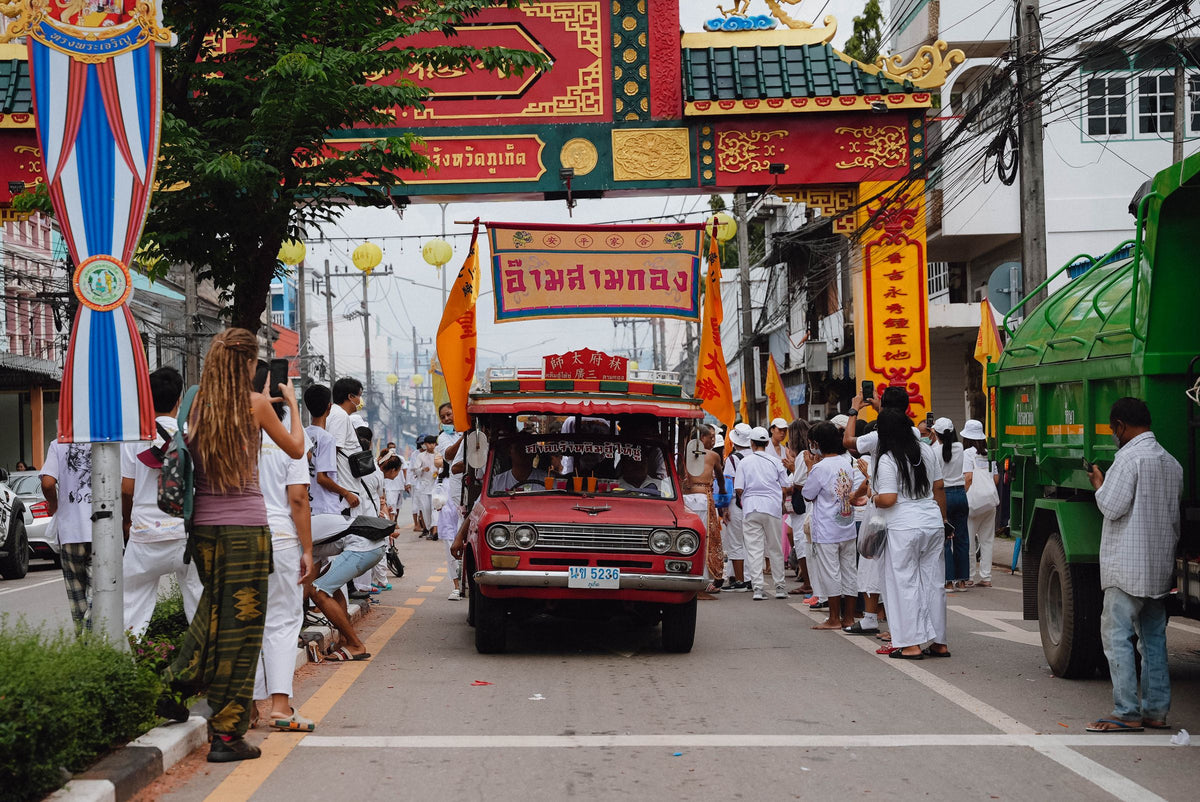 Vegetarian Festival parade passing under a ceremonial arch in Phuket Town