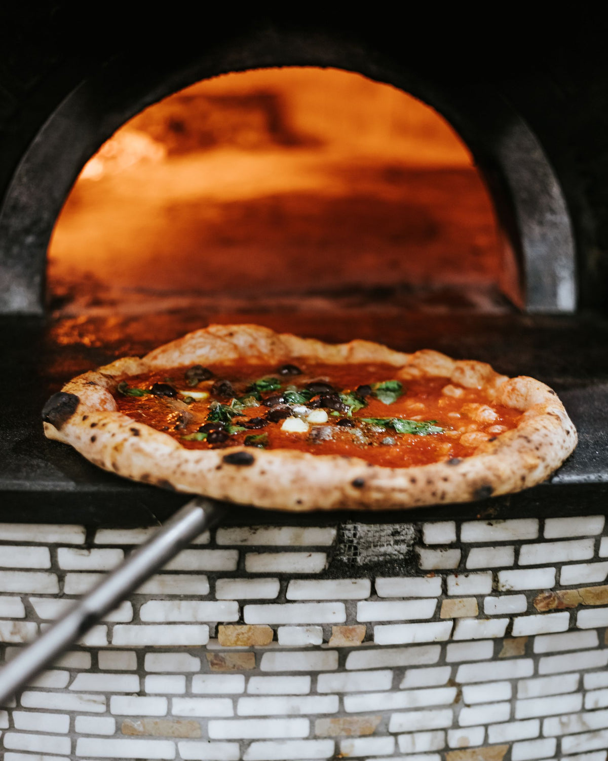 A pizza leaving the wood-fired oven in Naples