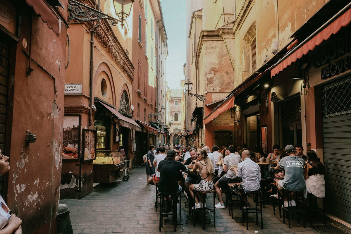 People dining outdoors on a lively Bologna street