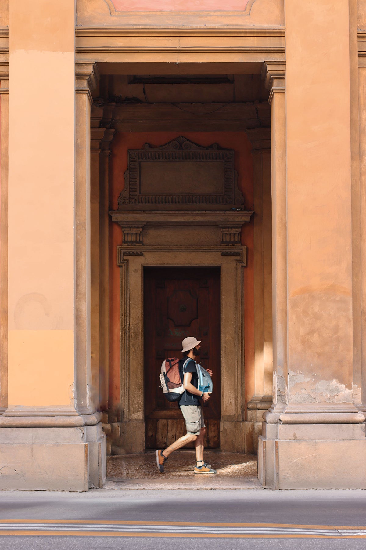 A backpacker walking past historic buildings in Bologna