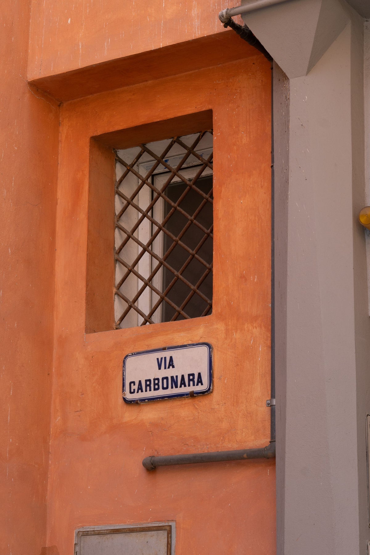 The Via Carbonara street sign on an orange facade