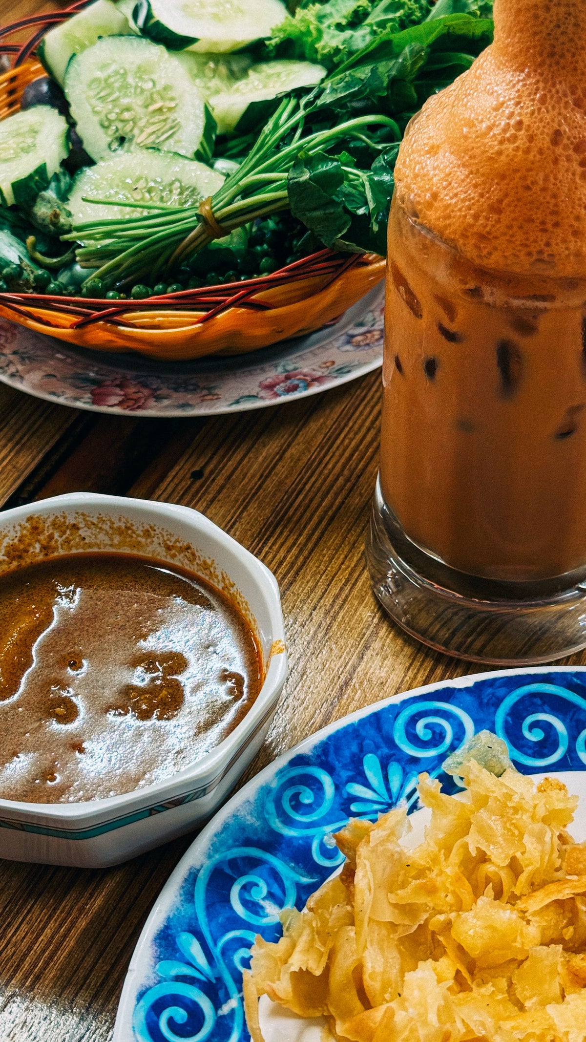 Thai meal with iced milk tea, fresh vegetables and dipping sauces in Phuket