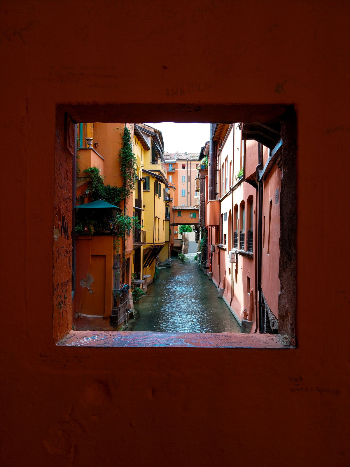 A canal view framed through a window, Bologna's hidden canals