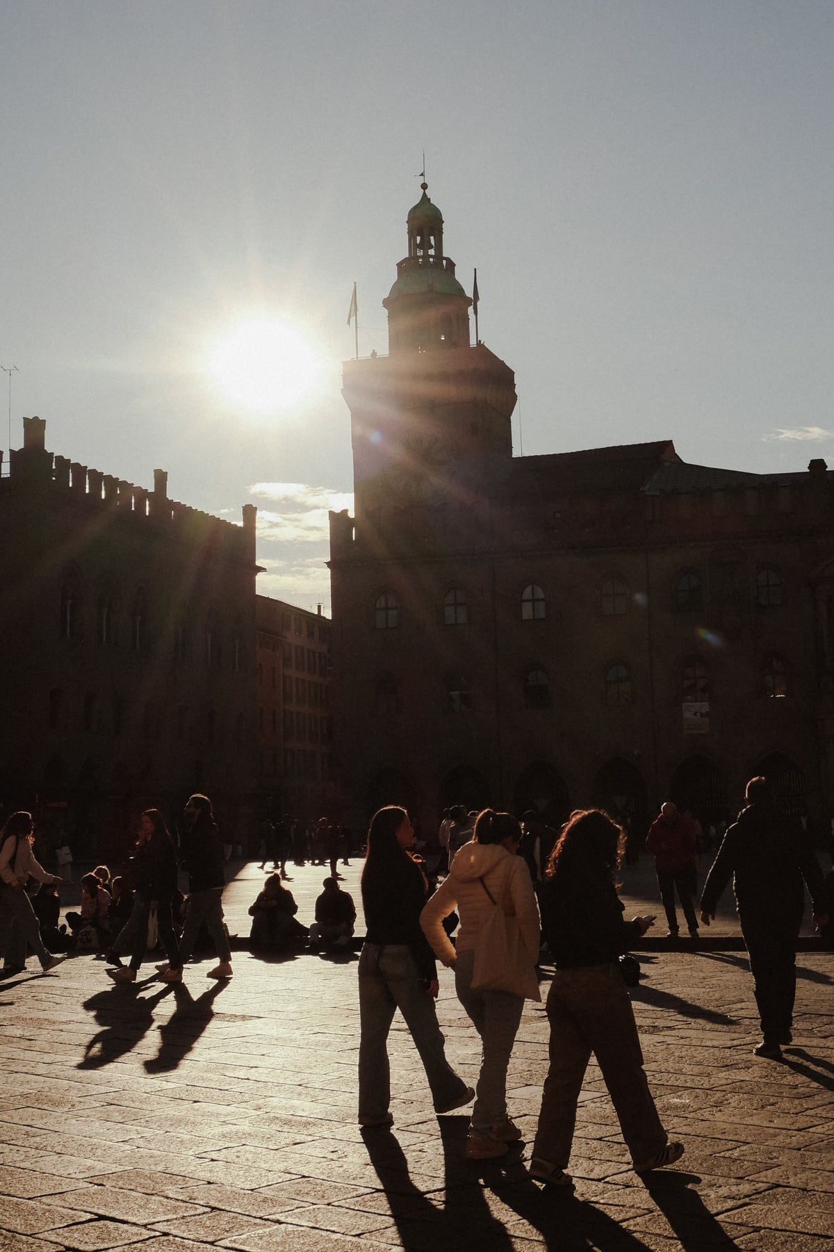 People enjoying the sunset in a historic Bologna piazza