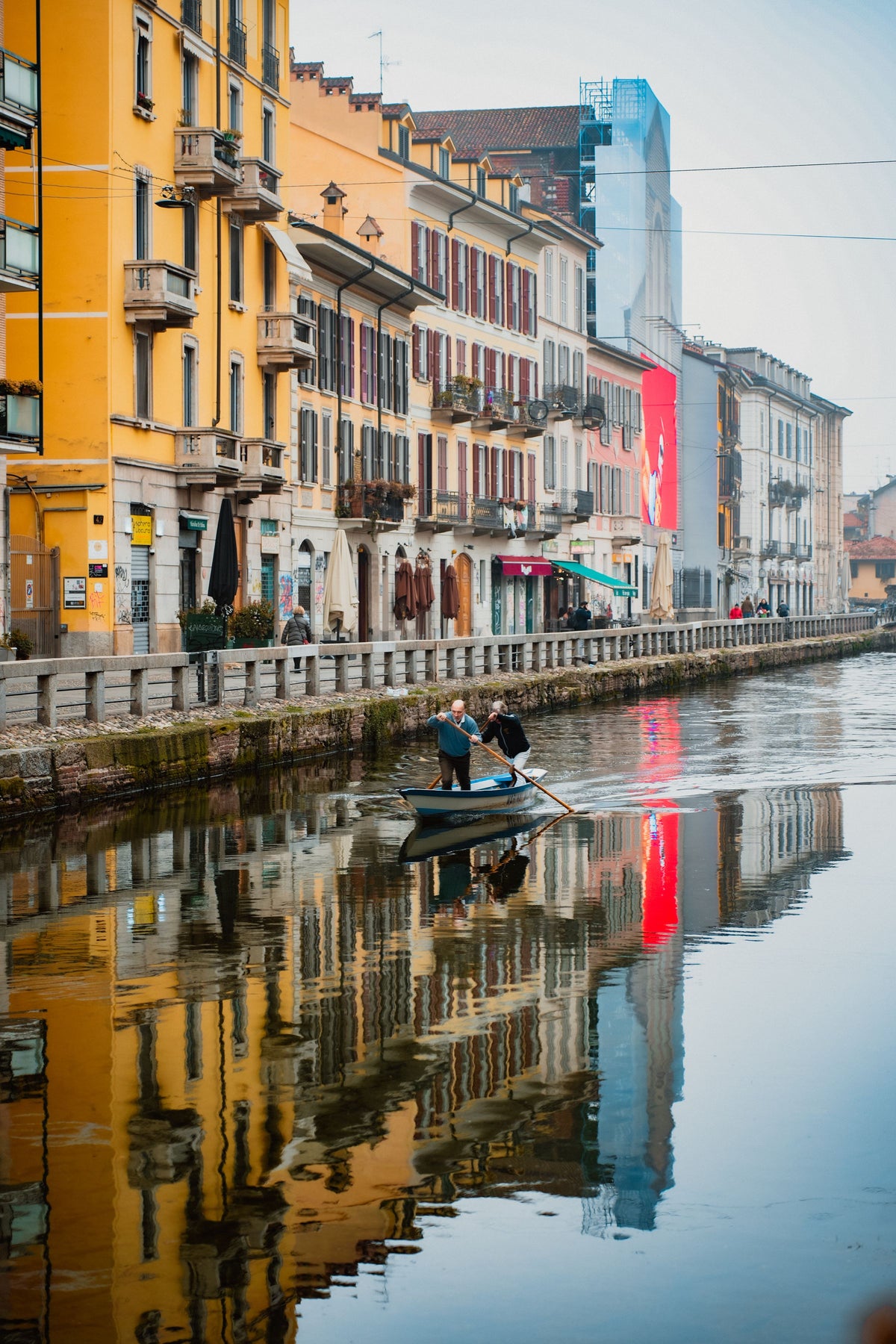 Rowing on the Navigli canal past colourful reflections