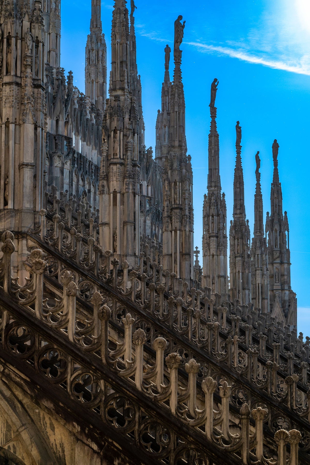 The ornate Gothic spires of the Duomo against a clear sky