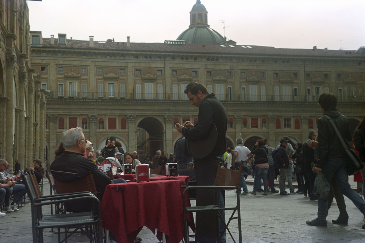 Café tables and people on a busy day in Piazza Maggiore
