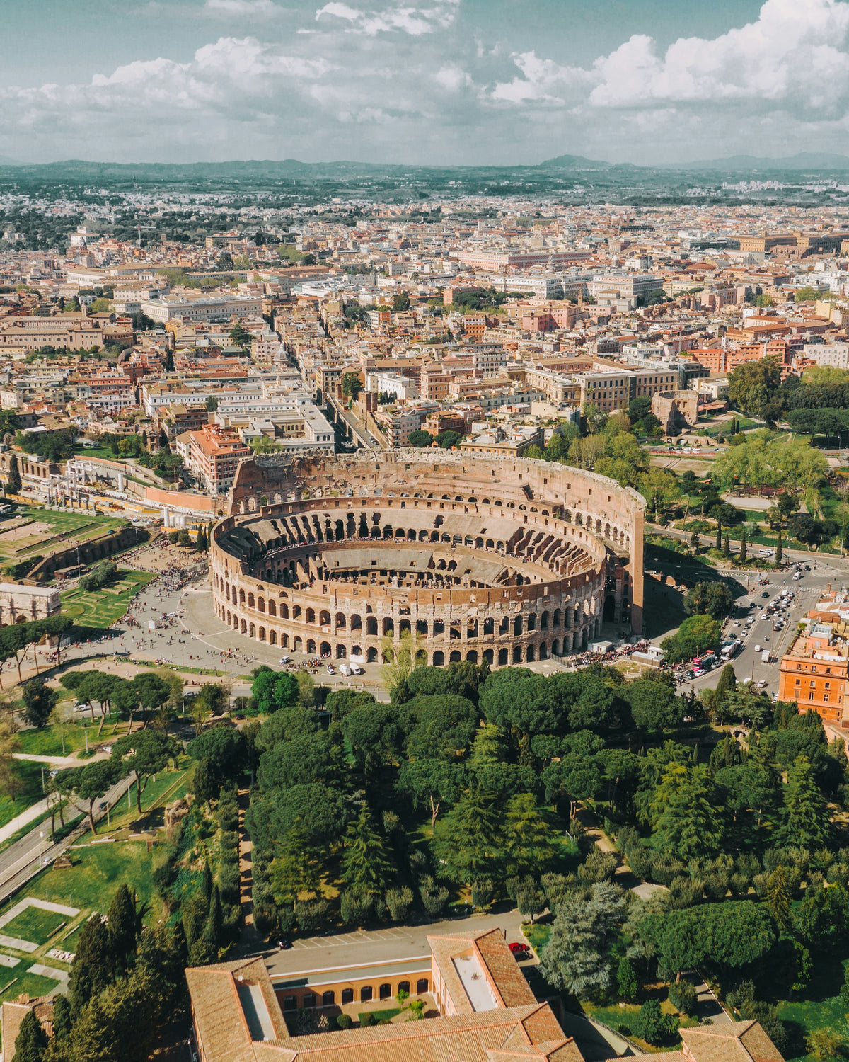 The Colosseum from above, ringed by parkland and the rooftops of Rome