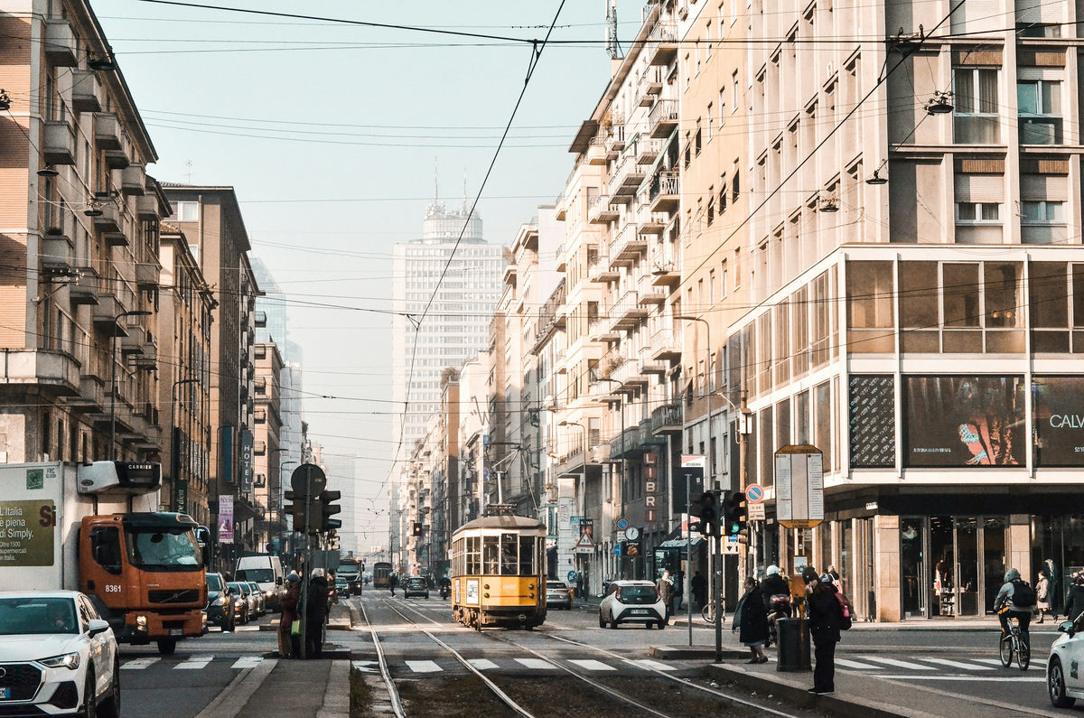 A yellow tram on a long, shop-lined Milan street