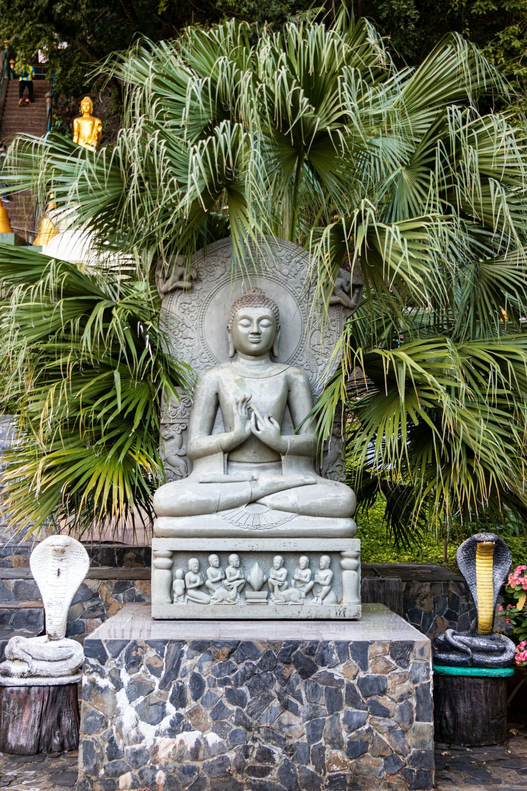 A Buddha statue among palms and ferns at Tiger Cave Temple