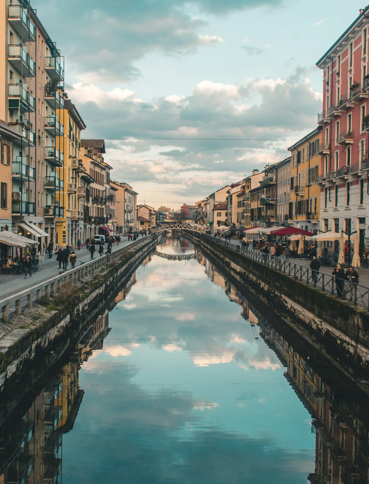 A Milan canal between buildings under a blue sky