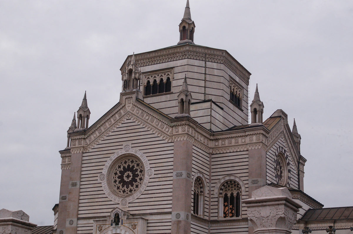 Monuments in a Milan cemetery under white clouds