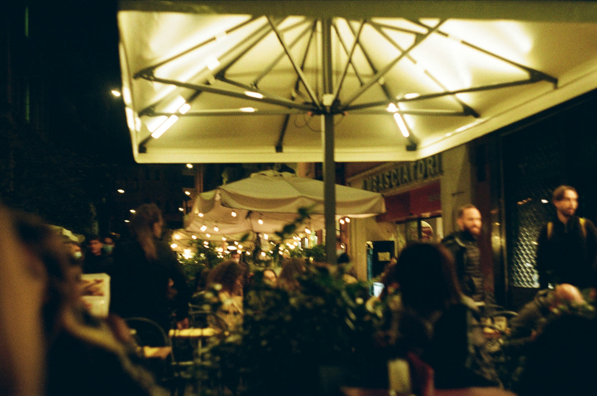 People sitting at outdoor tables under umbrellas in Bologna