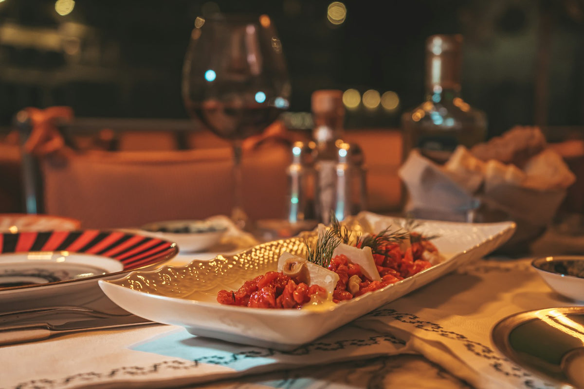 A plated starter and red wine on a candlelit table