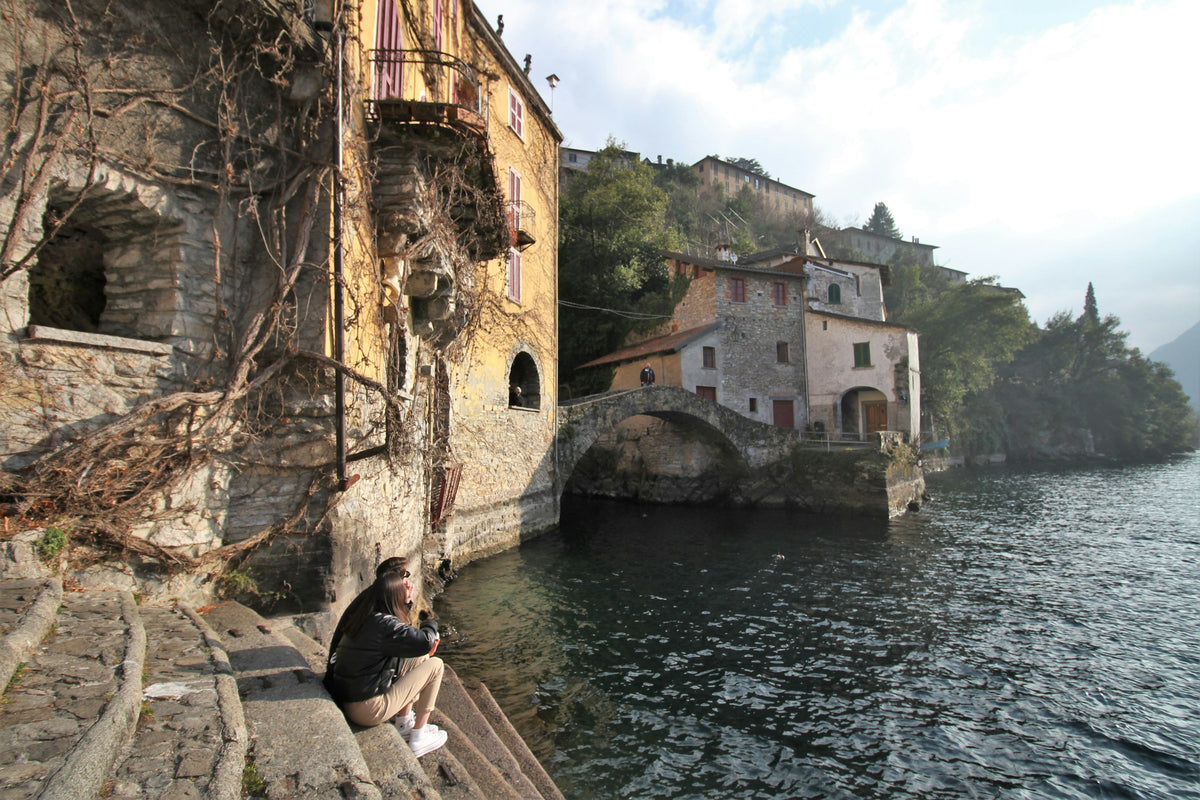 A person sitting on a ledge by the water at Nesso