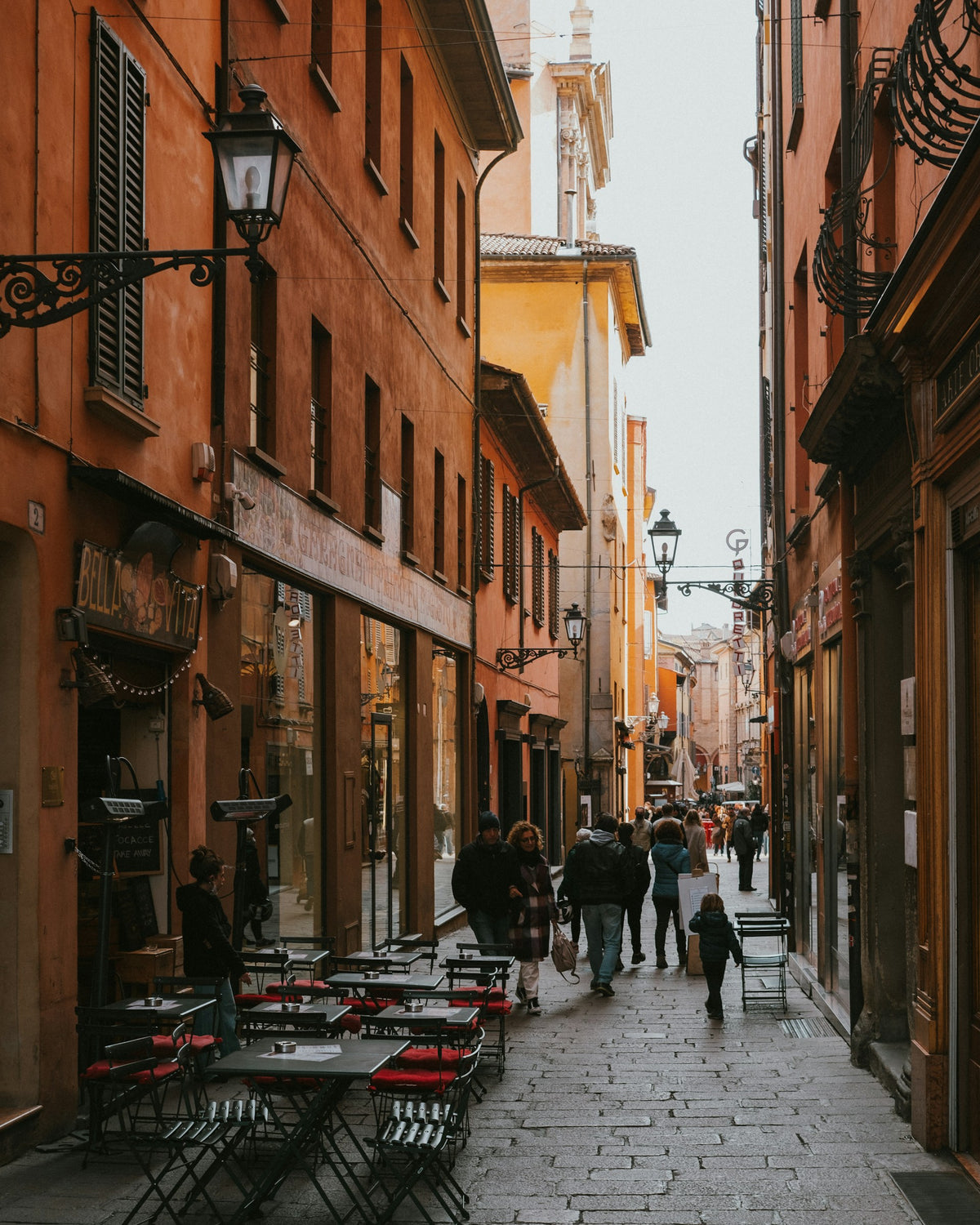 People walking down a street lined with tall buildings in Bologna