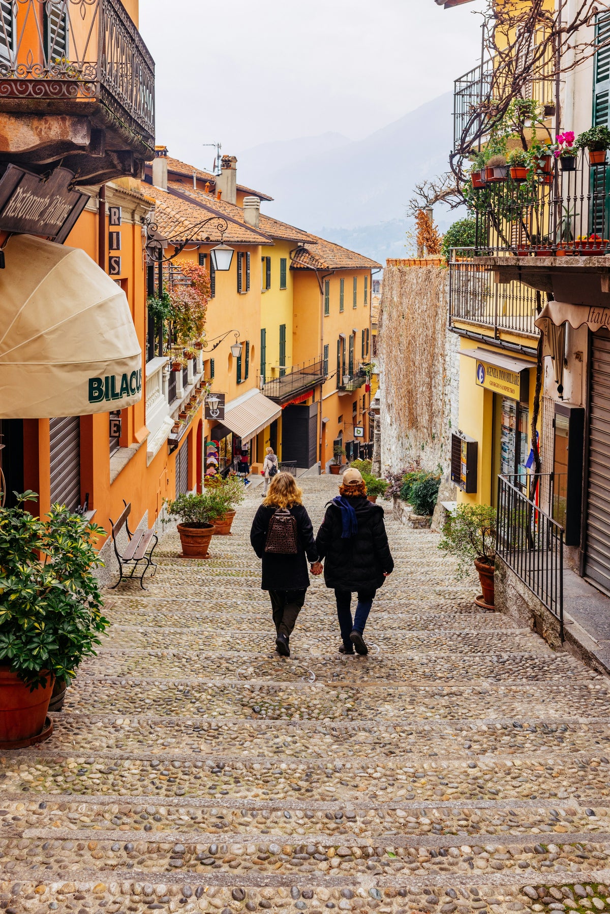 Two people walking down a cobblestone street in Bellagio