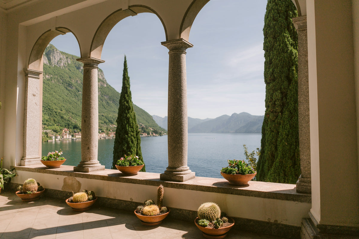 Potted cacti and flowers on a stone balcony above the lake in Varenna