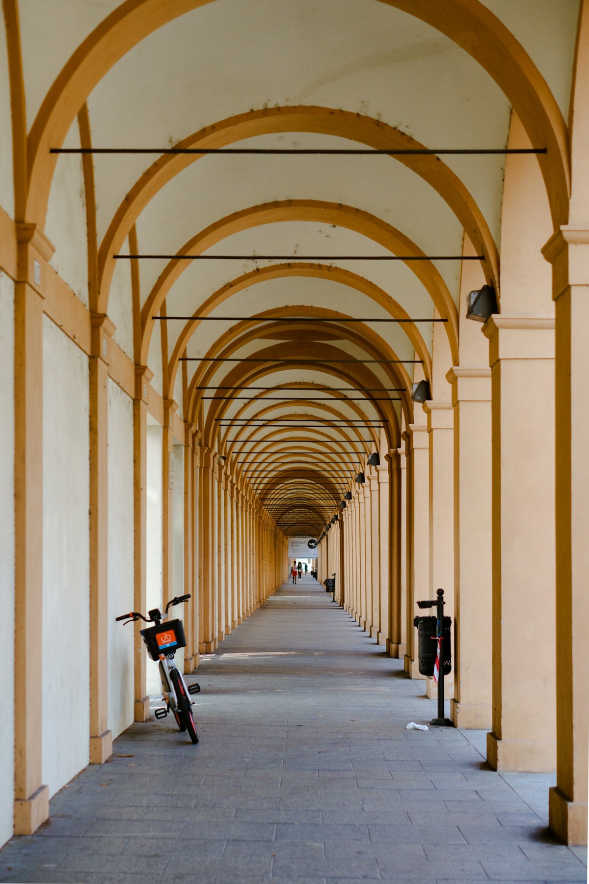 A bicycle parked in an empty portico gallery in Bologna