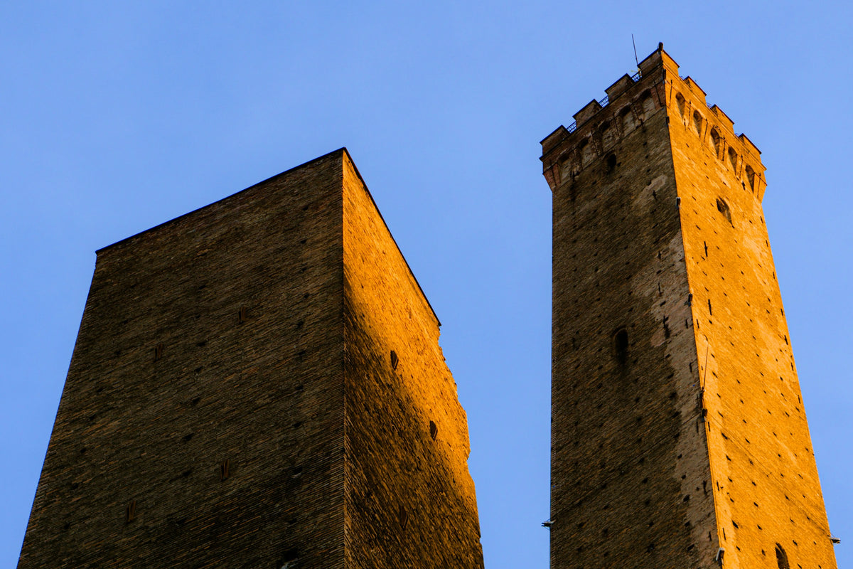 Two medieval stone towers against a blue sky in Bologna
