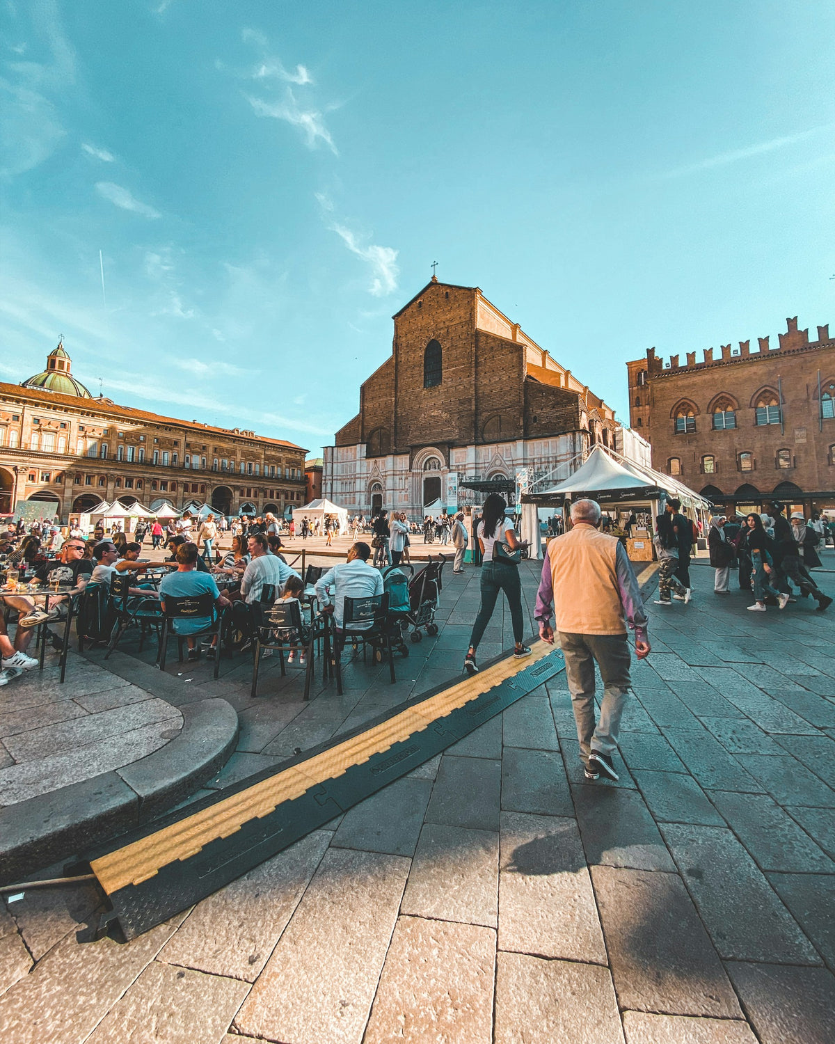 People sitting at outdoor tables on a Bologna street