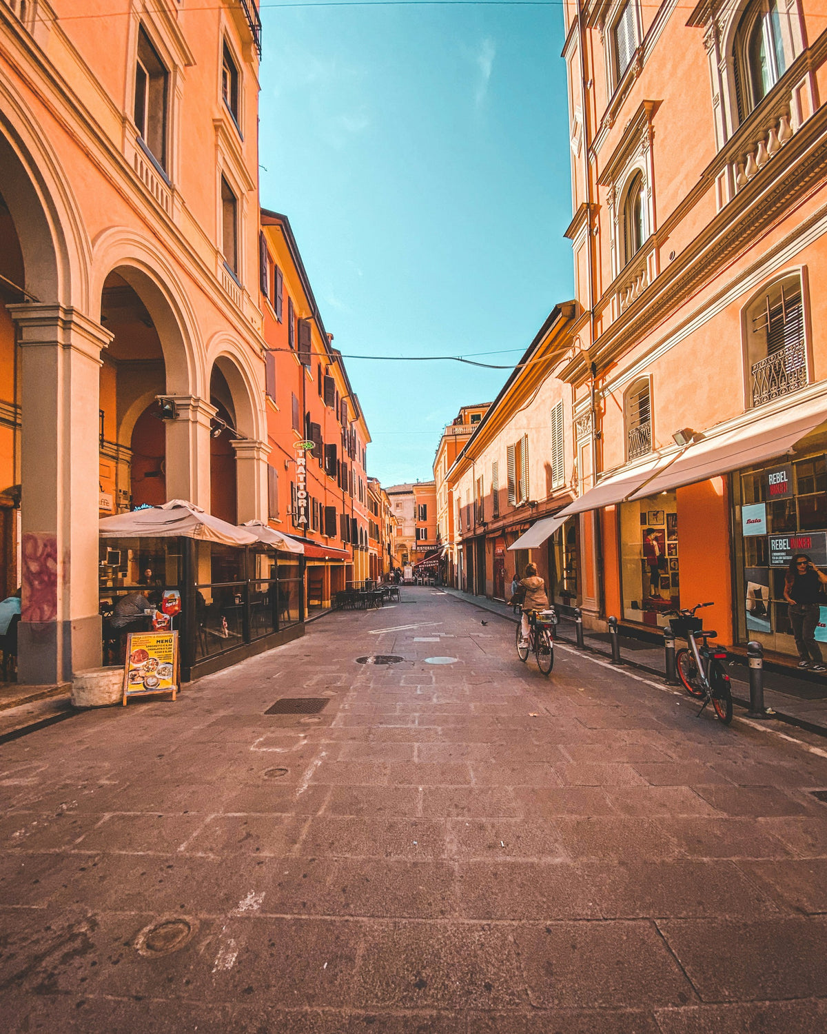 A cyclist riding between buildings on a Bologna street